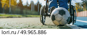 A person in a wheelchair playing soccer with a ball outdoors. Стоковое AI-изображение, AI-художник Данила Большаков / Фотобанк Лори