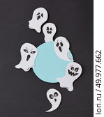 Greeting card, creative application with handmade paper terrible spirits smiling and laughing ghosts on a black background, place under text. Halloween concept. Flat lay.. Halloween party round frame with habdcrafted laughing flying scary ghosts, spirits, around it on a black background. Стоковое фото, агентство Ingram Publishing / Фотобанк Лори