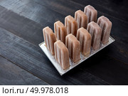 Plastic popsicle ice lolly form molds with making homemade chocolate ice creame and candies in ice pop molds on a wooden background with copy space. Cooking chocolate ice creame and candies in ice pop molds on a wooden background with copy space. Стоковое фото, агентство Ingram Publishing / Фотобанк Лори
