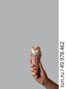 A girl’s hand holds a fruity vanilla ice cream with different pills in a waffle cone, ice cream flows over a female hand around a gray background with copy space for text.. Melting ice cream with pills in a waffle cone in a woman’s hand on a gray background with copy space. Стоковое фото, агентство Ingram Publishing / Фотобанк Лори
