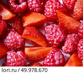 Natural freshly picked fruits in the red background with raspberry and strawberry. Close-up top view.. Close-up of a natural organic background made from ripe raspberries and strawberry slices. Стоковое фото, агентство Ingram Publishing / Фотобанк Лори