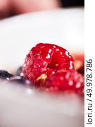 A white bowl with a natural diet breakfast - a close-up of raspberries in honey. Dietary food.. A close-up of raspberry poured honey in a white bowl. Стоковое фото, агентство Ingram Publishing / Фотобанк Лори