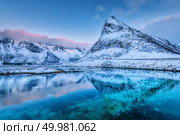 Beautiful snow covered mountains and blue sky with clouds reflected in water at dusk. Winter landscape with sea, snowy rocks, blue sky, reflection, at sunset. Lofoten islands, Norway at twilight. Стоковое фото, агентство Ingram Publishing / Фотобанк Лори