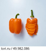 Two yellow peppers on a gray background. Halves of pepper with cut for cooking. Flat lay. Yellow pepper half and chopped into pieces on gray background. Стоковое фото, агентство Ingram Publishing / Фотобанк Лори
