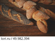 Assortment of fresh baguettes close up on a wooden brown background. Baguette on a wooden table. Стоковое фото, агентство Ingram Publishing / Фотобанк Лори