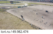 Above of racing track at Kiev hippodrome and jockeys during horse races on his horses. Aerial drone view .. Bird-eye view of the hippodrome and train horses with people in Kyiv city, Ukraine. Редакционное фото, агентство Ingram Publishing / Фотобанк Лори
