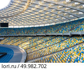 KIEV, UKRAINE - July 19, 2018. National Sports Complex Olimpiysky - the inside part with a football field, tribunes in a blue and yellow colors. Aerial view from drone in a summer time.. KYIV, UKRAINE - July 19, 2018. Panoramic view of construction of the stadium roof, tribunes with yellow and blue seats of NSC Olimpiysky. Редакционное фото, агентство Ingram Publishing / Фотобанк Лори