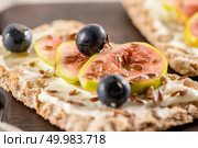 Canape or crostini with multigrain  crispread with cream cheese and fresh fig slices on a wooden board. Delicious appetizer ideal as an aperitif. Стоковое фото, агентство Ingram Publishing / Фотобанк Лори