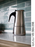 Modern stainless geyser coffee macker on kitchen on the induction panel on blue tiles background.. stainless geyser coffee maker on a background of blue tiles. Стоковое фото, агентство Ingram Publishing / Фотобанк Лори