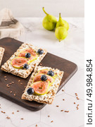 Canape or crostini with multigrain  crispread with cream cheese and fresh fig slices on a wooden board. Delicious appetizer ideal as an aperitif. Стоковое фото, агентство Ingram Publishing / Фотобанк Лори