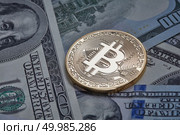 One gold coin in the background of dollar bills. Conceptual image for worldwide cryptocurrency and digital payment system.. One gold coin in the background of dollar bills. Стоковое фото, агентство Ingram Publishing / Фотобанк Лори