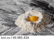 Flour and raw egg on the kitchen table, ingredients for kneading the dough. Pile of flour and egg on the kitchen table. Стоковое фото, агентство Ingram Publishing / Фотобанк Лори