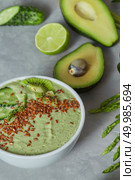 green detox smoothy bowl with spinach, cucumber, kiwi, and flax seeds with avocado, slice lime on a stone background. Vegan meal and detox concept. green spinach smoothy bowl topped with cucumber, avocado and flax seeds on stone background. Стоковое фото, агентство Ingram Publishing / Фотобанк Лори