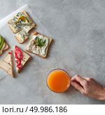 Top view of different kinds of sandwiches for tasting or having break isolated on table. Glass of orange juice not far from it. Sandwiches with cheese, avocado, etc.. Different kinds of sandwiches. Стоковое фото, агентство Ingram Publishing / Фотобанк Лори