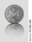 Silver coin monero with reflection on white glossy background. Conceptual image for worldwide cryptocurrency and digital payment system.. Silver coin monero on a white glossy background. Стоковое фото, агентство Ingram Publishing / Фотобанк Лори