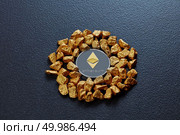 Gold nuggets in the form of a circle and a coin ethereum on a black concrete background. Concept of financing Bitcoin cryptocurrency in Noble metal. Etereum coin and golden nuggets on a black concrete background. Business, finance and technology concept. Стоковое фото, агентство Ingram Publishing / Фотобанк Лори