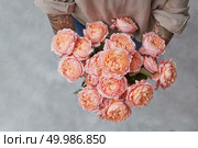 Girls hands with bouquet of flowers on a gray background with copy space.. Beautiful bouquet of pink roses in womans hands with tatoo. Top view. Стоковое фото, агентство Ingram Publishing / Фотобанк Лори