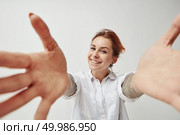 Portrait of a happy young girl with outstretched open hands to embrace. Joyful greeting. Young woman smiling with her arms open on white background. Стоковое фото, агентство Ingram Publishing / Фотобанк Лори