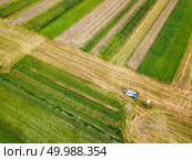 Preparation of soil for sowing of winter crops. Aerial view from the drone of the field after harvest with combine and red car on it.. Aerial view frome a drone of combine plowing the ground after harvesting on the field in the autumn time. Стоковое фото, агентство Ingram Publishing / Фотобанк Лори