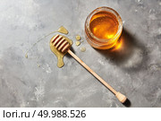 Jewish holiday Rosh Hashanah background with organic floral honey on a gray stone background, copy space. Top view. Pure natural sweet goodness.. Sweet flower natural honey in a jar and wooden spoon on a gray concrete table. Top view. Jewish New Year healthy holiday. Стоковое фото, агентство Ingram Publishing / Фотобанк Лори