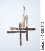 Collection of old metal with wooden handle forks and knives on a gray background with copy space. Vintage Collection. Flat lay. Pattern from metalic old knives and forks with wooden handles presented on a gray background with space for text. . Flat lay. Стоковое фото, агентство Ingram Publishing / Фотобанк Лори