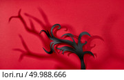 On a red background scary shadows and handcraft paper branches with copy space for text. Halloween card. Flat lay. Pattern of shadows and handmade paper black branch on a red background with space for text. Halloween card. Flat lay. Стоковое фото, агентство Ingram Publishing / Фотобанк Лори