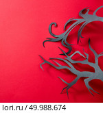 Mystical composition of handcraft paper a tree from a pattern of shadows on a red background with space for text. Halloween card. Flat lay. Handcraft black tree from paper on a red background with reflection of shadows and copy space for text. Creative Halloween layout. Flat lay. Стоковое фото, агентство Ingram Publishing / Фотобанк Лори