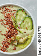 Vegetarian healthy smoothies from green organic vegetables with flax seeds in a white bowl on a grey background, table. Top view. Top view of a green smoothie from cucumber, kiwi, asparagus with flax seeds in a white bowl on a grey background. Стоковое фото, агентство Ingram Publishing / Фотобанк Лори