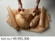 Pieces of bread in female hands and on parchment paper on a gray background. Assortment of different types of bread. Стоковое фото, агентство Ingram Publishing / Фотобанк Лори