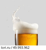 Close-up of cold beer with foam and splash on a gray background. Close-up of cold beer with foam. Стоковое фото, агентство Ingram Publishing / Фотобанк Лори
