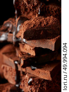 chocolate syrup being poured onto dark chocolate pieces isolated on black. Heap of broken pieces chocolate. Стоковое фото, агентство Ingram Publishing / Фотобанк Лори