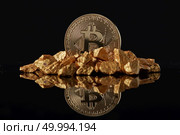 Golden Bitcoin Coin and mound of gold with reflection on a dark glossy background. Concept of financing Bitcoin cryptocurrency in Noble metal. Golden Bitcoin Coin and mound of gold on a dark background. Стоковое фото, агентство Ingram Publishing / Фотобанк Лори