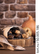 Roasted chestnuts in a paper cone, on a rustic kitchen countertop. Стоковое фото, агентство Ingram Publishing / Фотобанк Лори