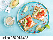 Toasts with feta cheese, tomatoes, avocado, pomegranate, pumpkin seeds and flaxseed sprouts. Diet breakfast. Delicious and healthy food. Flat lay. Top view. Стоковое фото, агентство Ingram Publishing / Фотобанк Лори
