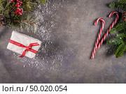 Christmas background with Christmas gift, pine cones, red striped canes on background with Fir branches. Xmas and Happy New Year composition. Flat lay, top view. Стоковое фото, агентство Ingram Publishing / Фотобанк Лори