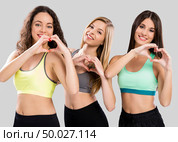 Three beautiful and athletic girls making heart shapes with hands. Стоковое фото, агентство Ingram Publishing / Фотобанк Лори