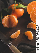 Fresh mandarin oranges or tangerines with leaves on textured dark background. Стоковое фото, агентство Ingram Publishing / Фотобанк Лори