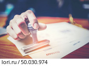 Close-up hand stamping of businessman for signing approval on documents , business concept. Стоковое фото, агентство Ingram Publishing / Фотобанк Лори