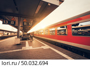Beautiful railway station with modern red commuter train at colorful sunset in Nuremberg, Germany. Railroad with vintage toning. Стоковое фото, агентство Ingram Publishing / Фотобанк Лори