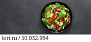 Spinach salad with fresh cucumbers, tomato, onion, pomegranate, sesame seeds and cashew nuts on black background. Healthy vegan food. Top view. Banner. Стоковое фото, агентство Ingram Publishing / Фотобанк Лори