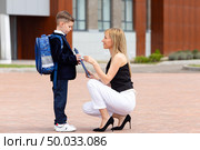 Mom accompanies her first-grader son to school, kissing and hugging him, back to school, the parent gives the child to the first grade. Mom meets a student from school. High quality photo. Стоковое фото, фотограф Ирина Михайличенко / Фотобанк Лори