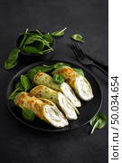 Savory crepes with spinach and feta cheese on black background. Стоковое фото, агентство Ingram Publishing / Фотобанк Лори