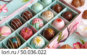 A box overflowing with various types of chocolates, including truffles, pralines, and caramels, creating a tempting display of sweet treats. Стоковое AI-изображение, AI-художник Данила Большаков / Фотобанк Лори