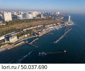 Town coastline with modern buidings, waterfront and sea beach with blue water on a background of blue sky. Aerial view from drone.. Natural landscape with costline of city Odesa, Ukraine. Seascape with sandy beach and blue water. Aerial view from drone. Стоковое фото, агентство Ingram Publishing / Фотобанк Лори