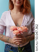 Sexy smiling girl holding in her hands a bouquet of fresh pink roses on a blue background with copy space. Creative layout for postcard. A bouquet of pink roses is holding in hands a sexy red-haired girl around a blue background with copy space. Valentine’s day concept. Стоковое фото, агентство Ingram Publishing / Фотобанк Лори
