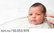 Baby with serious expression receiving an ear checkup. Стоковое AI-изображение, AI-художник Ольга Невская / Фотобанк Лори
