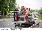Рабочие с флагом в рука в автовышке в городе Руза в мае 2025. Редакционное фото, фотограф Диана Лукьянова / Фотобанк Лори