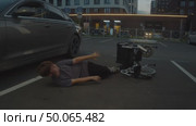 A child with special needs has fallen out of a wheelchair onto the asphalt on a city street and cannot get back up. Стоковое видео, видеограф Strunov David / Фотобанк Лори