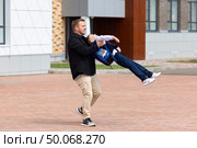 Happy father spinning his son around outside after school lessons while playing and spending time together. Concept of friendly family and fatherhood. Copy space. High quality photo. Стоковое фото, фотограф Ирина Михайличенко / Фотобанк Лори