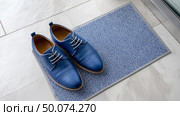 Brown dress shoes neatly placed on a doormat at home entrance. Стоковое AI-изображение, AI-художник Katsiaryna Repich / Фотобанк Лори